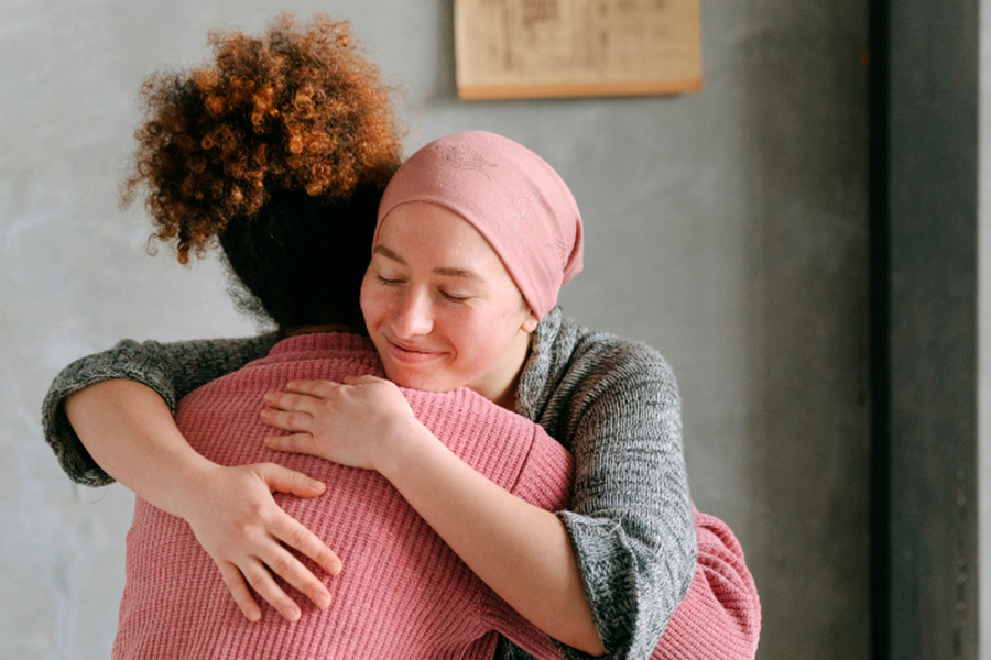 Abrazo de dos mujeres, una de ellas lleva un pañuelo rosa